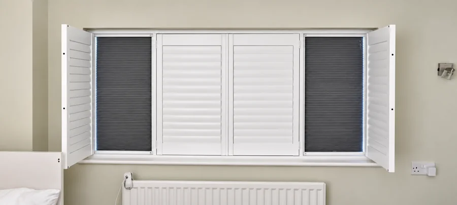 Close-up of white shutters and dark blackout blinds