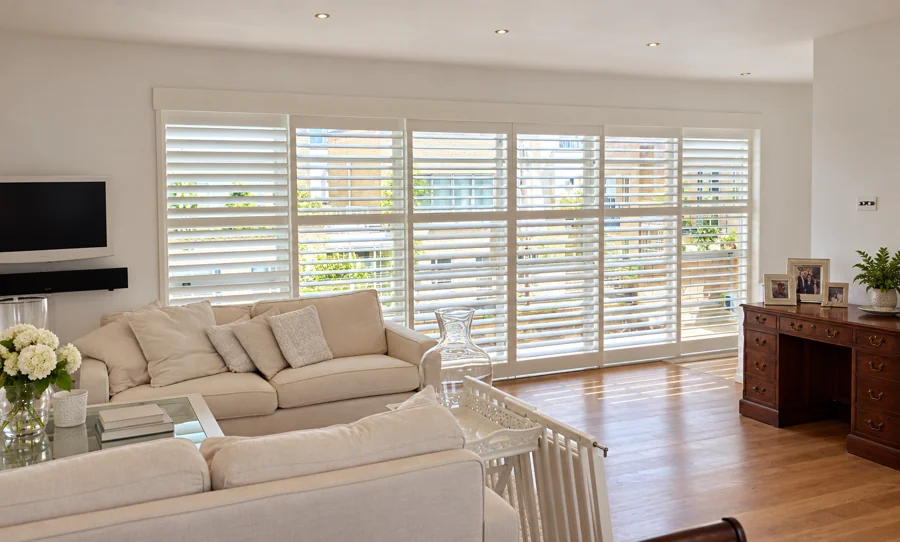 White patio-door shutters across a wide living-room opening
