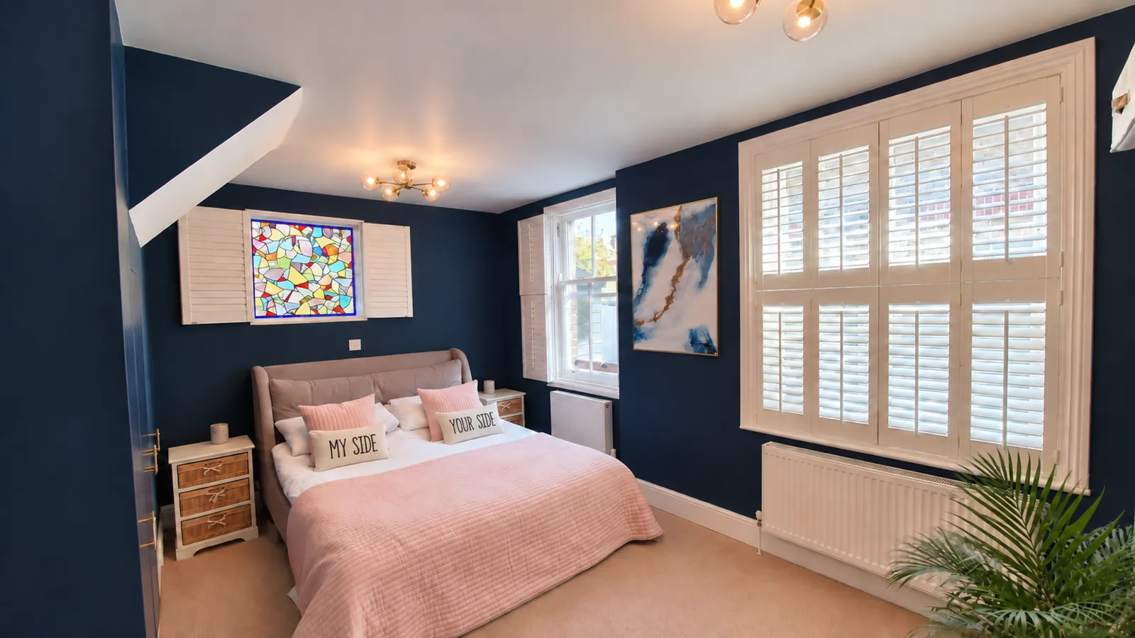 White tier-on-tier shutters in a navy and pink bedroom