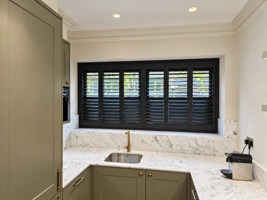 Black plantation shutters above a kitchen worktop