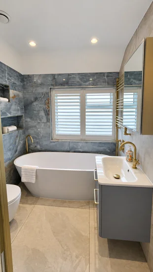 White shutters above a bath in a tiled bathroom