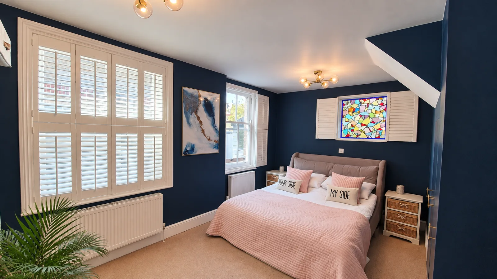 White tier-on-tier shutters in a navy and pink bedroom