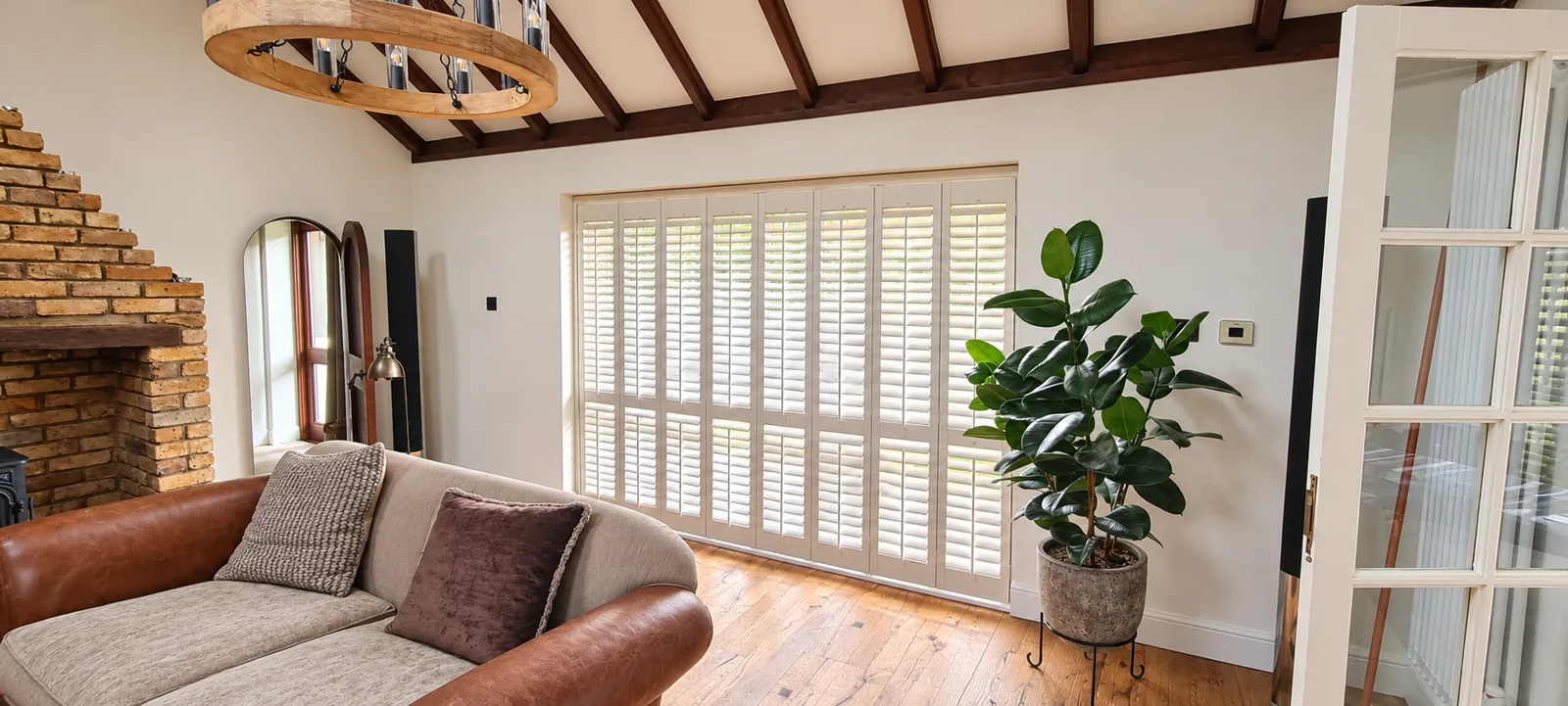 White shutters across glazed doors beneath timber beams