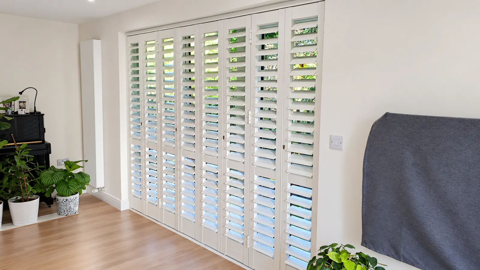 White louvred aluminium security shutters across tall windows