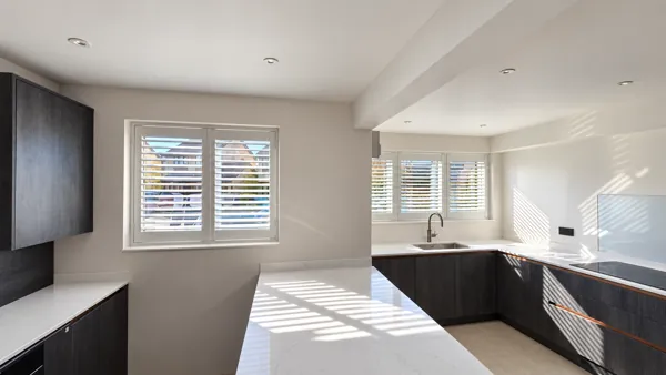 Full-height kitchen shutters with a T-post layout above the sink in Gloucester