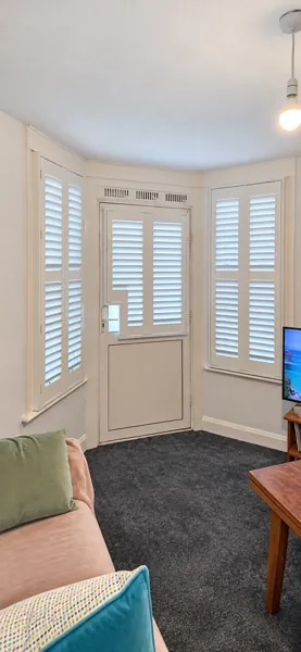 Composite shutters around a West London bay with a door-mounted shutter and bespoke handle cutout