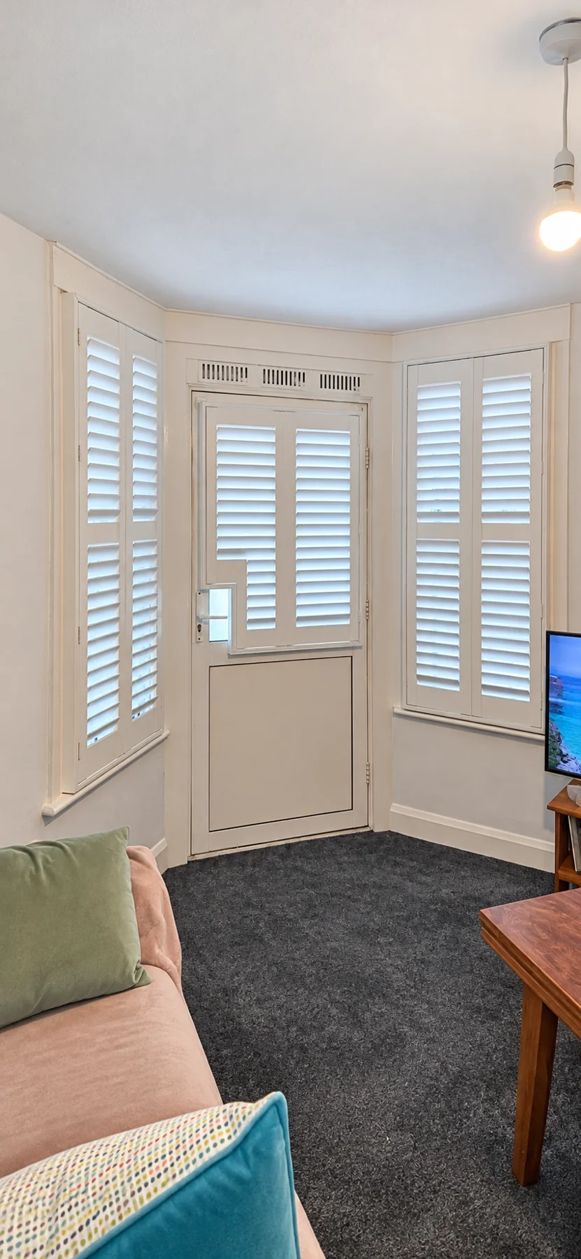 Composite shutters around a West London bay with a door-mounted shutter and bespoke handle cutout